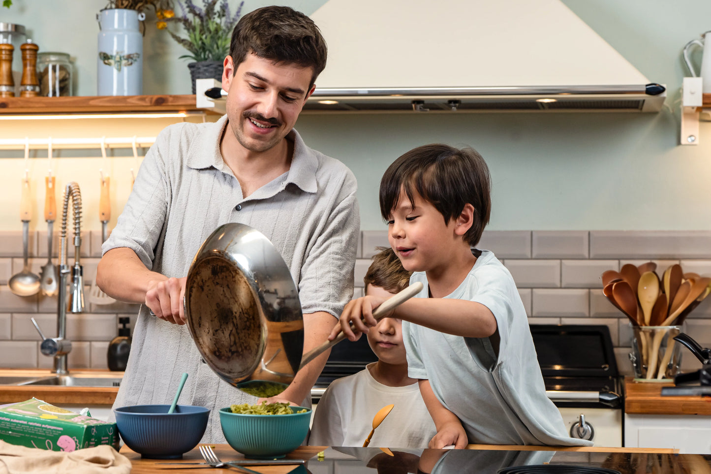 Vater hält Pfanne und der Sohn tut sich das Essen aus der Pfanne auf.