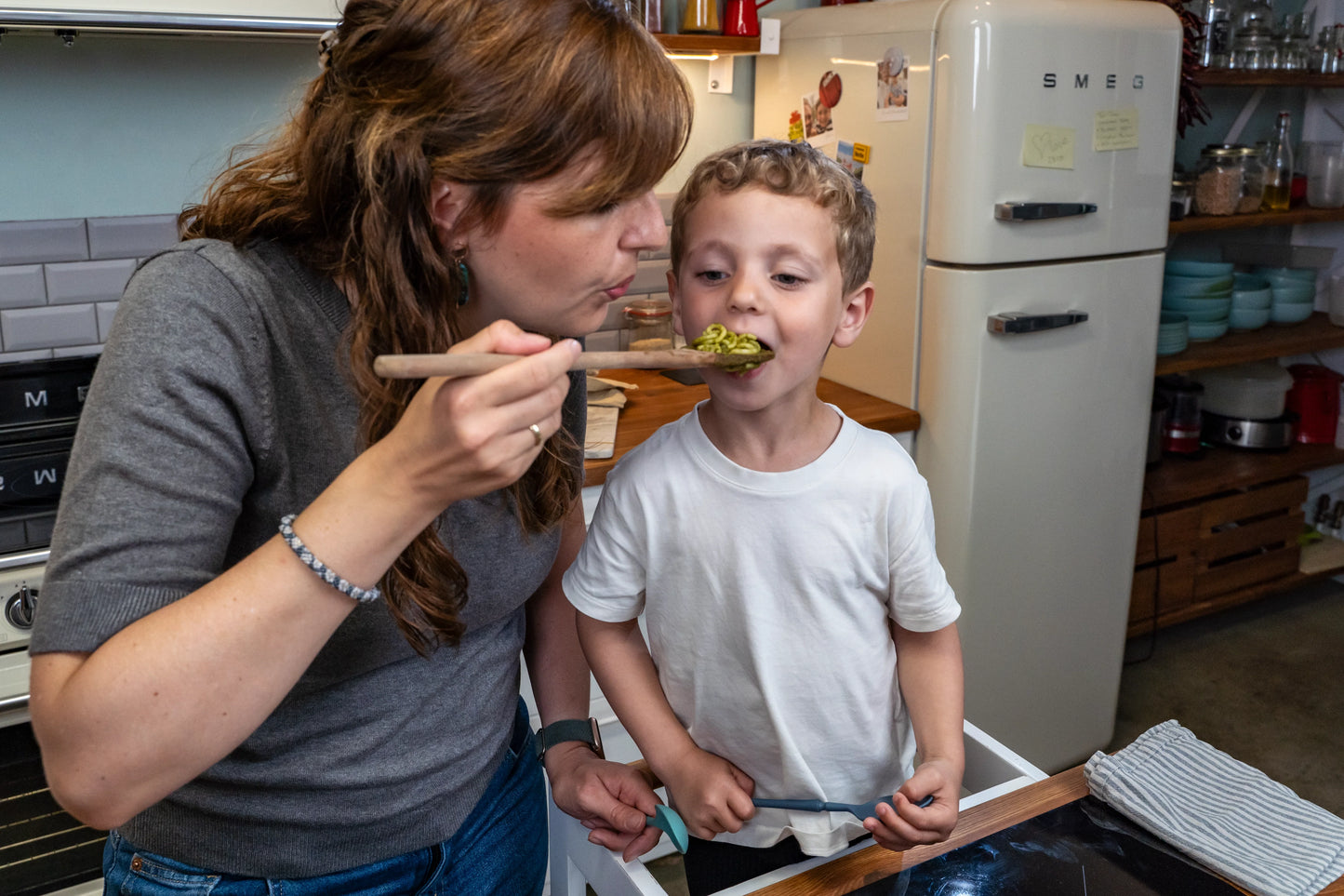 Mutter füttert ihren Sohn mit Kochlöffel.