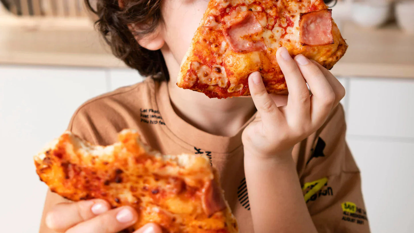 Ein Kind hält zwei Stücke Pizza in der Hand. Das eine ist zur hälfte aufgegessen, von dem anderen wird gerade abgebissen. 