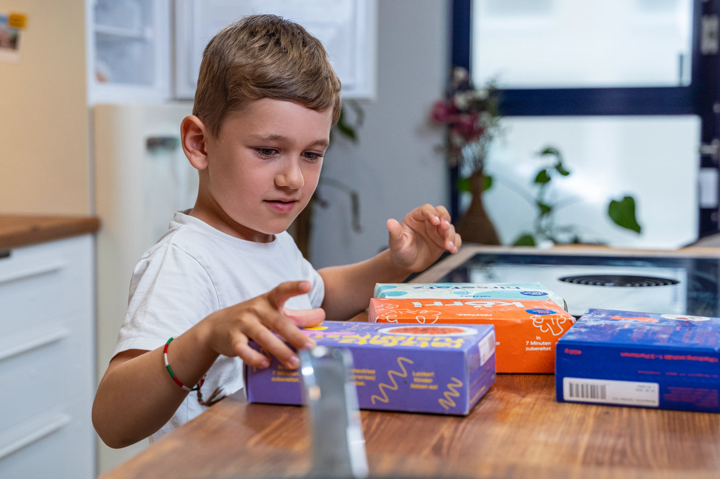 Junge steht vor verschiedenen Produkten und überlegt welches Gericht er essen möchte