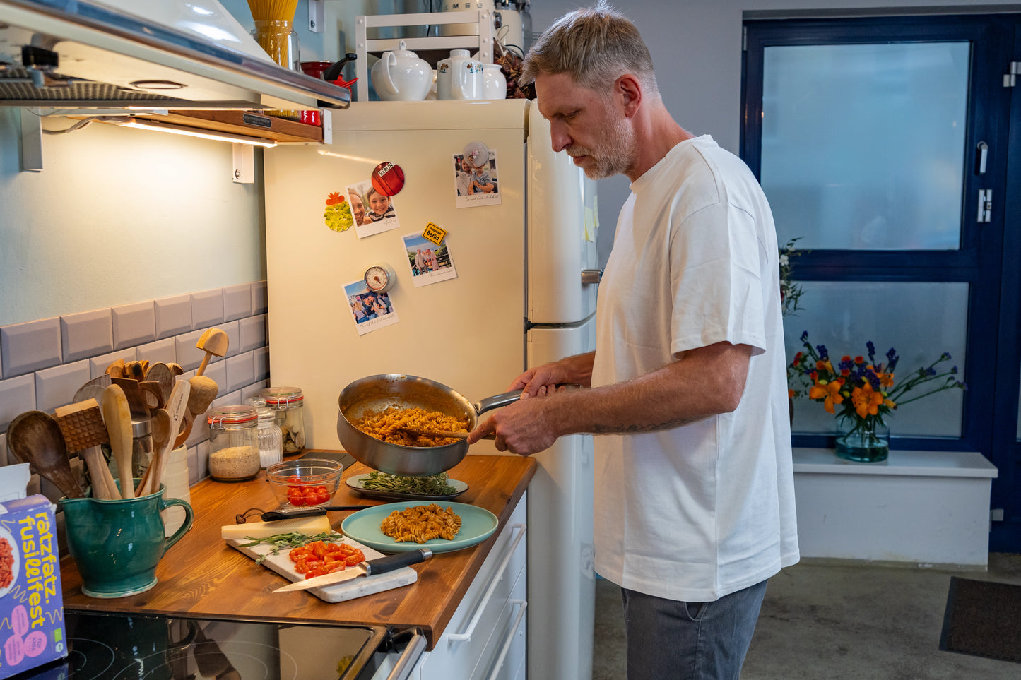 Mann steht mit Pfanne in der Küche und bereitet Essen vor