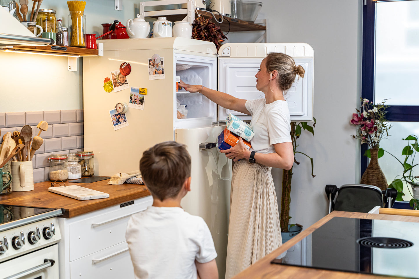 Frau räum Tiefkühlfach ein, Junge sieht ihr dabei zu