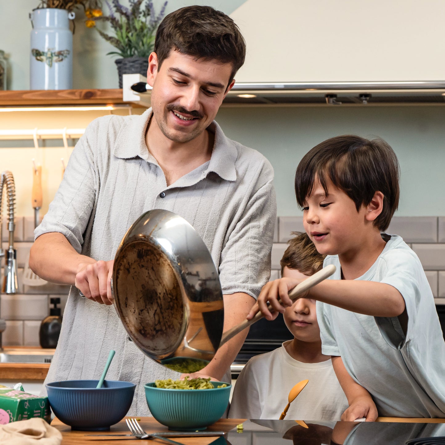 Vater hält die Pfanne und Kinder tuen sich das Essen auf.